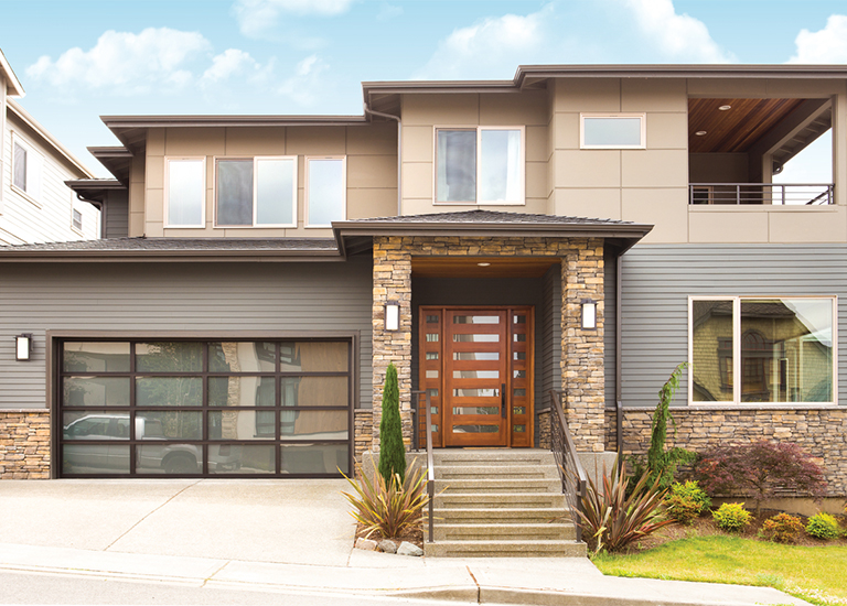 bronze aluminum garage door on modern home with driveway and yard