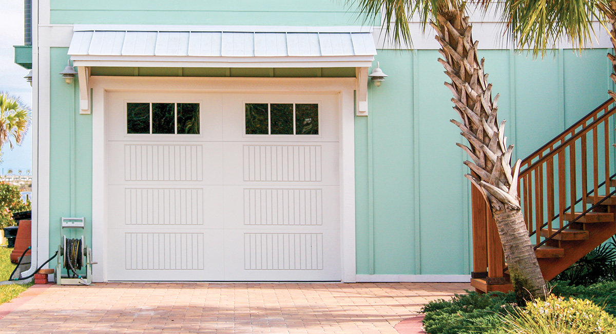 white fiberglass garage doors with six vertical windows on blue beach home