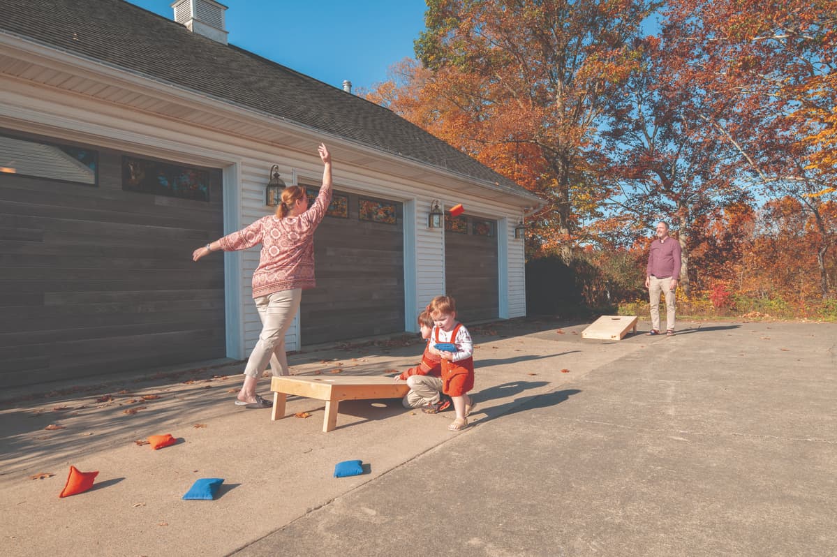 family playing cornhole in front of Wayne dalton 8300 carbon oak garage doors