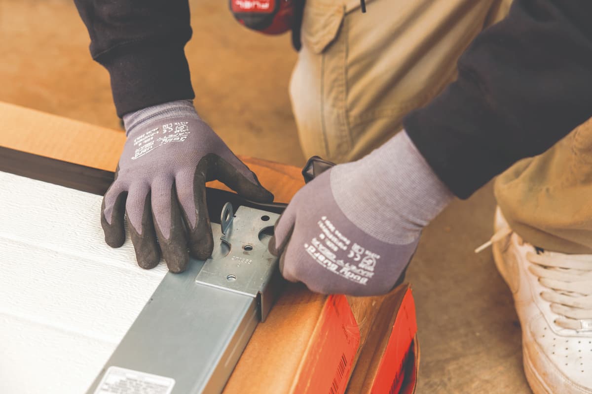 Technician installing garage door weather stripping