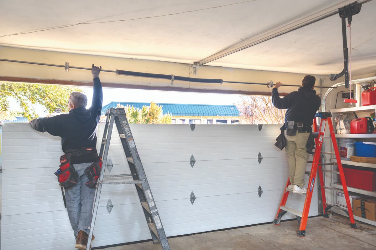 Wayne Dalton Sales & Service technicians on ladders installing a new garage door spring • Wayne Dalton Sales & Service technicians on ladders installing a new garage door spring