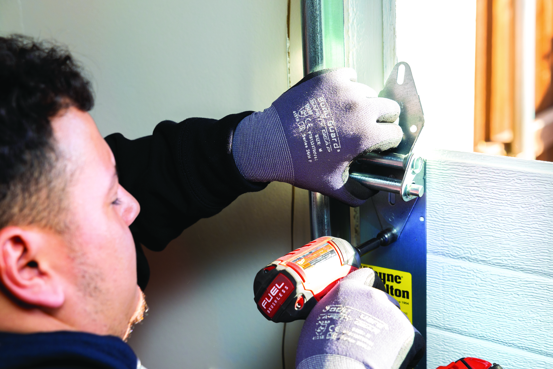 Wayne Dalton Sales & Service technician installing garage door panel with drill