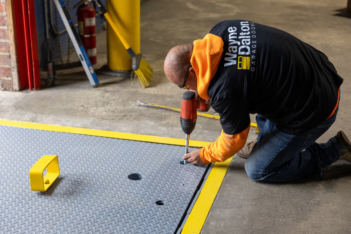 Wayne Dalton Sales & Service technician performing maintenance on mechanical pit leveler